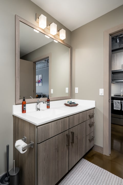 A sleek modern bathroom with a wooden vanity and a large mirror.
