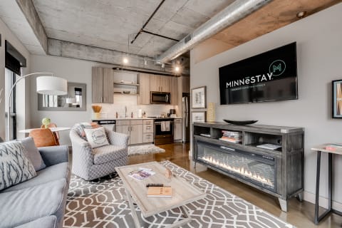 Modern apartment interior featuring a living area with a sofa, armchair, coffee table, and kitchen.