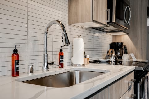 Contemporary kitchen with a stainless steel sink, chrome faucet, and amber soap dispensers.