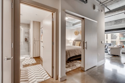 Interior view of a modern apartment hallway with a bathroom and bedroom visible.