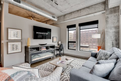 Modern living room with gray sofa, coffee table, and large windows.