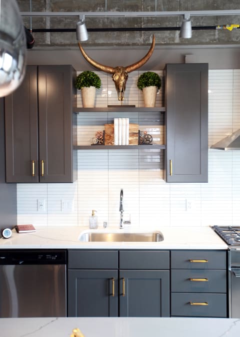 Contemporary kitchen with gray cabinets, white tile backsplash, and gold accents.