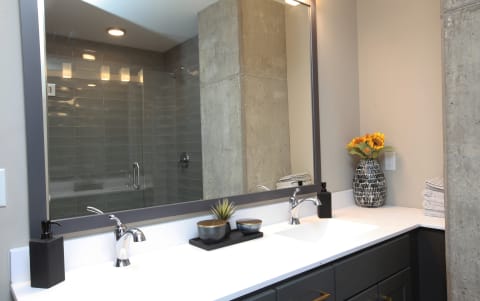 A modern bathroom with a large mirror, chrome faucets, and decorative elements.