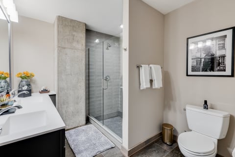 Contemporary bathroom featuring a walk-in shower, black vanity, and yellow flowers in a vase.