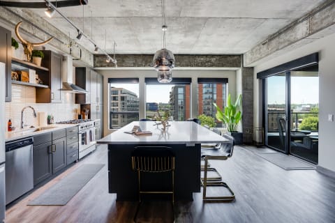 A contemporary kitchen with dark cabinetry, a white island, and large windows overlooking the city.