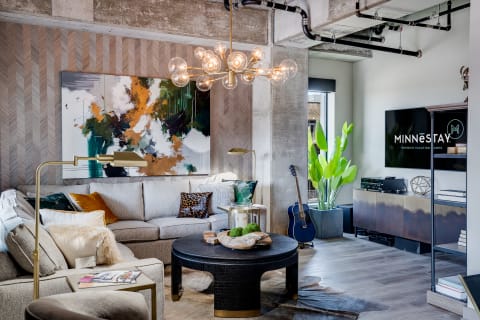 A contemporary living room featuring a light grey sofa, abstract art, and elegant decor.