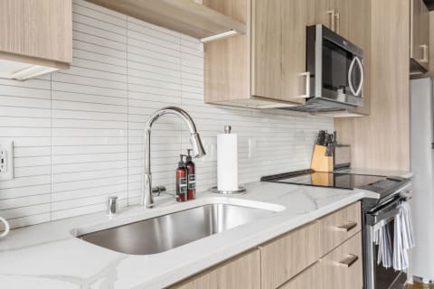 Modern kitchen with marble counter, stainless steel sink, and wooden cabinetry.