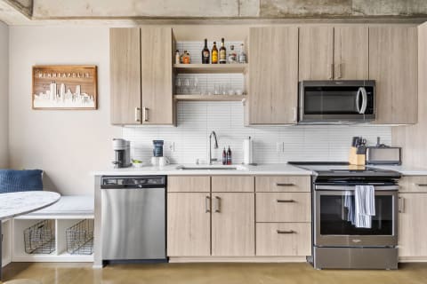 Modern kitchen featuring light wood cabinets, stainless steel appliances, and a marble dining table.