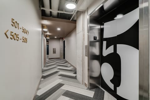 Contemporary building hallway with elevator and directional signage.