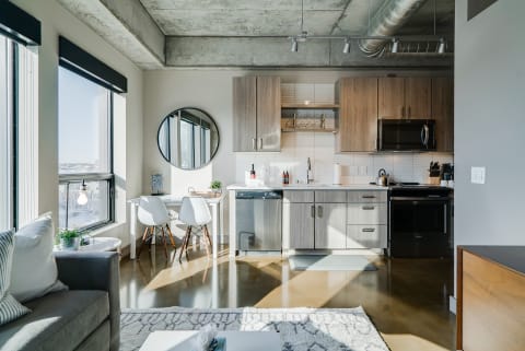 Modern kitchen and living area with concrete ceilings and large windows.