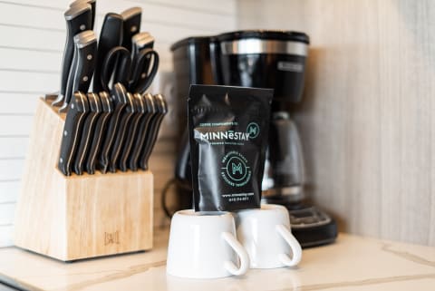 Two white coffee cups beside a pouch of coffee in a kitchen.