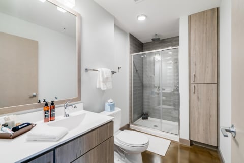 A modern bathroom featuring a glass shower, a white vanity, and polished floors.