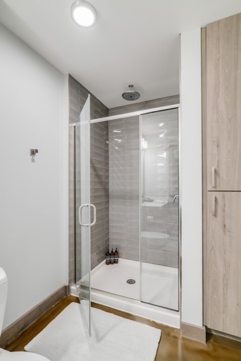 A modern bathroom shower with glass enclosure and gray tiles.