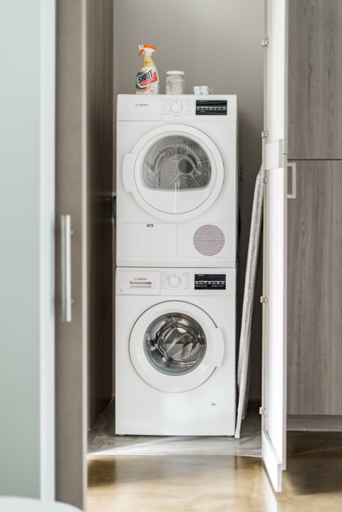 A stacked washer and dryer with Bosch branding in a well-lit laundry area.