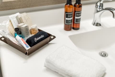 Organized bathroom sink countertop with toiletries and a navy towel.