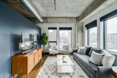 Contemporary living room featuring a navy blue wall, gray sofa, and urban skyline view.