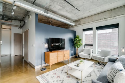 Contemporary living room featuring a blue accent wall, wooden media console, and modern furniture.