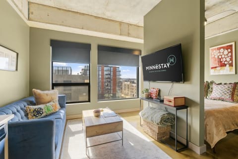 Interior of a modern living space with a blue couch, coffee table, and a mounted TV.