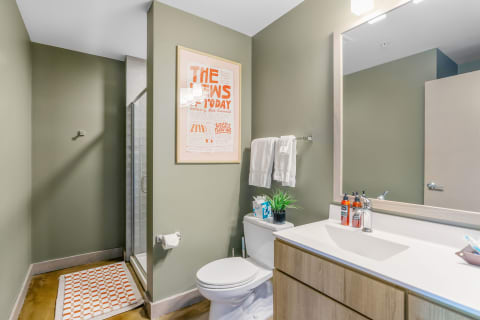 Modern bathroom featuring green walls, a shower, and a white sink area.