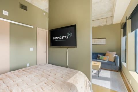 Cozy vacation rental room with a bed, television, and living area.