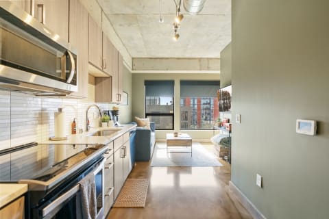 A modern studio apartment featuring a compact kitchen and a cozy living area with a blue couch.