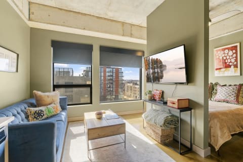 Cozy living space featuring a blue sofa, a wooden coffee table, and a mounted television.