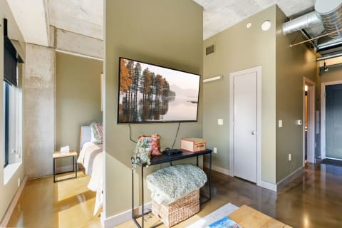 Modern apartment interior with olive green walls, a mounted TV, and warm decor elements.