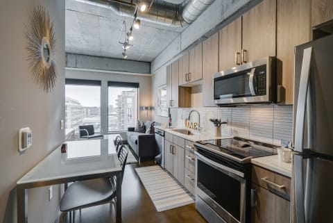 A contemporary kitchen and dining space in an apartment featuring stainless steel appliances and a stylish design.