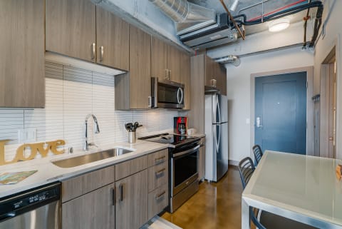 Contemporary kitchen with gray cabinets, stainless steel appliances, and a stylish dining area.