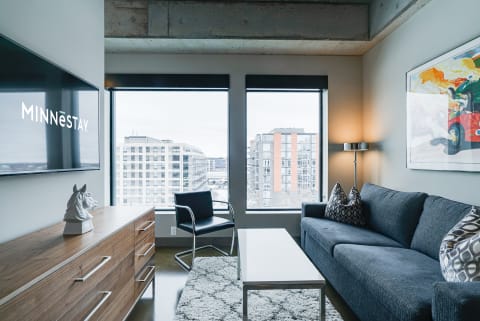 Stylish modern living room with a large window, TV, and cozy furnishings.