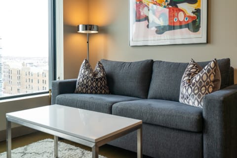 Contemporary living room with gray sofa, decorative pillows, and city view through the windows.