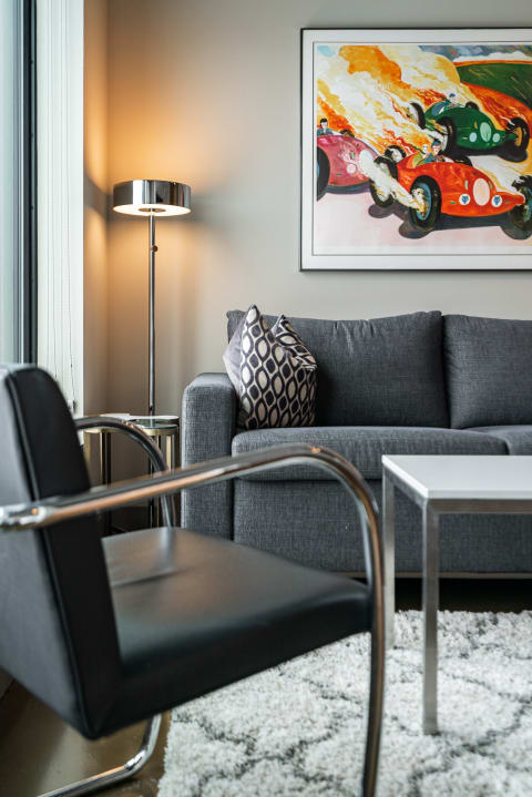 Contemporary living room featuring a gray sofa, colorful racing artwork, and a stylish lamp.