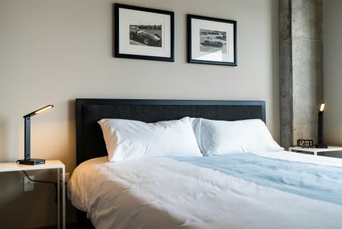 A well-decorated bedroom with black and white car photos, a neatly made bed, and modern lighting.