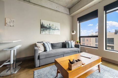 Modern living room featuring a grey sofa, wooden coffee table, and abstract wall art.