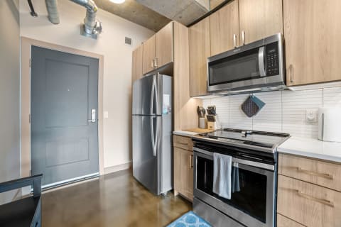 Interior view of a modern kitchen with stainless steel appliances and light wood cabinets.