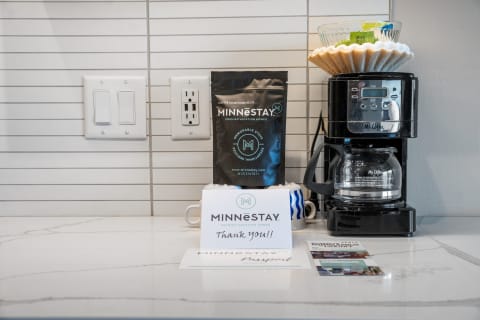 A coffee maker next to MINNESTAY coffee bag and a thank you note on the kitchen counter.