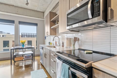 Modern kitchen with stainless steel appliances and large windows allowing natural light.