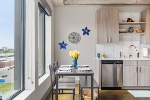 Modern kitchen and dining area with large windows, floral decor, and a bouquet of yellow tulips.