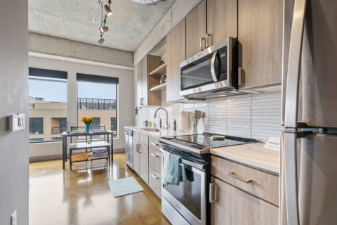Modern kitchen featuring stainless steel appliances and a dining table with flowers.