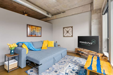 Modern living room featuring a blue sofa, yellow tulips, and industrial elements.