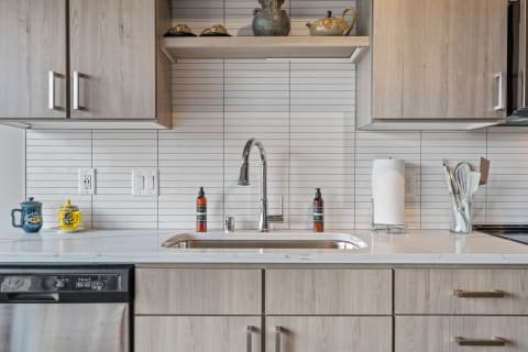 Modern kitchen sink area with wooden cabinets and decorative items.
