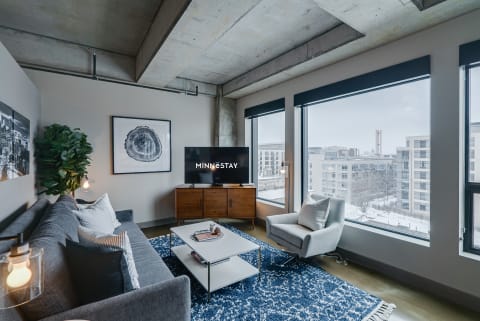 Stylish urban living room with gray sofa, television, and large windows showing snow outside.