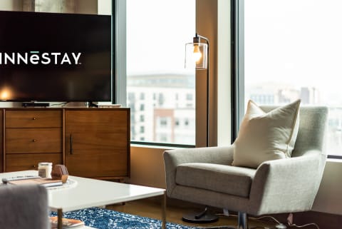 Cozy modern living room with a gray chair and an INNESTAY logo on a TV.