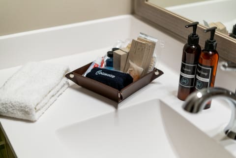 Bathroom countertop featuring a tray with toiletries and a folded towel.