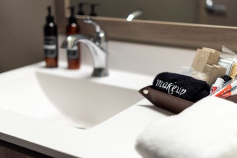 A contemporary bathroom sink area displaying products and a makeup towel.