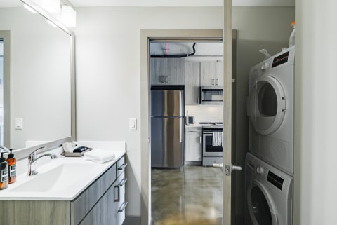 Modern bathroom with vanity and kitchen view beyond.