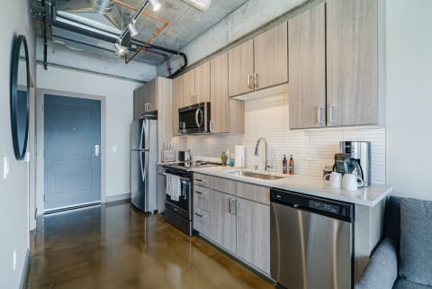 Contemporary kitchen featuring light wood cabinets, stainless steel appliances, and a glossy floor.