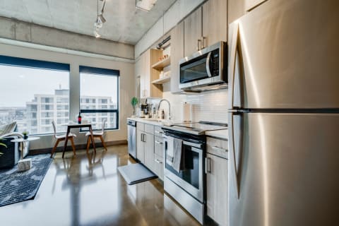 Contemporary kitchen with stainless steel appliances and a small dining table by the window.