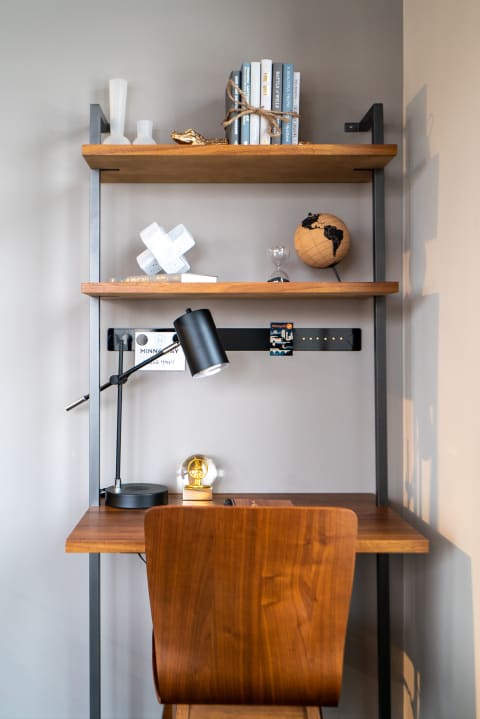 Modern workspace featuring a wooden desk, chair, and shelves with decor and books.