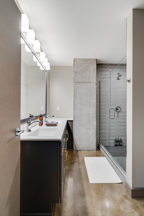Modern bathroom with a double vanity, geometric lights, and a glass shower.
